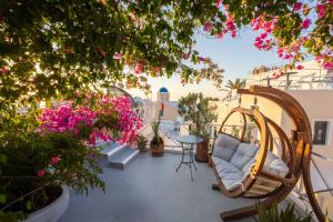 a balcony with a chair and flowers and a table at Santorini Paradise Cave Houses in Oia