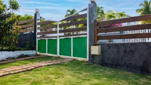 a fence with green doors in a yard at Appartement charmant à Baie Mahault avec belle terrasse – 30 m² in Baie-Mahault