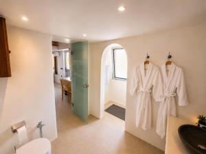 a bathroom with white robes hanging on a wall at iLocal Premium Services suite in Zefiría +27 photos