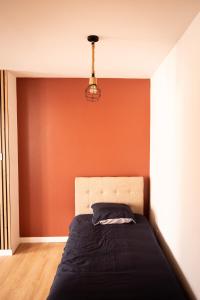 a bedroom with a bed with an orange wall at Le nid bourbourgeois in Bourbourg