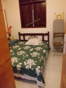 a bedroom with a bed with a green and white blanket at Appartement spacieux à Sainte-Rose - 120 m² - Terrasse ensoleillée in Sainte-Rose