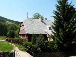 a house with a metal roof and a tree at Penzion Pod můstky in Harrachov