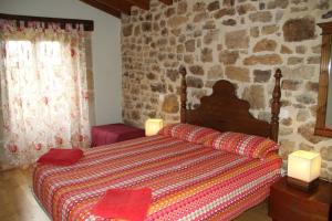 a bedroom with a bed and a stone wall at Charming House in La Cavada with Jacuzzi in La Cavada