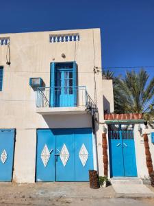 a building with blue doors and a balcony at Dar Essadeg Bis in Tataouine