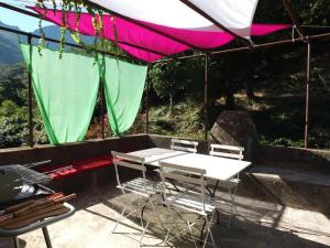 a table and chairs under a pink and green umbrella at Appartement raffiné à Feliceto - 120 m² avec vue sur montagne in Feliceto
