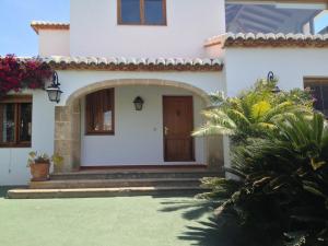a white house with a brown door and some plants at Seaside villa in Jávea with private pool in Jávea