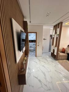 a living room with a television and a marble floor at Flowers in Bouznika