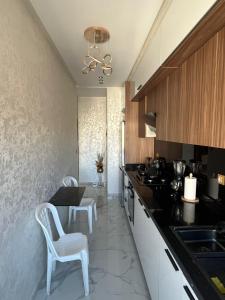 a kitchen with white chairs and a black counter top at Flowers in Bouznika