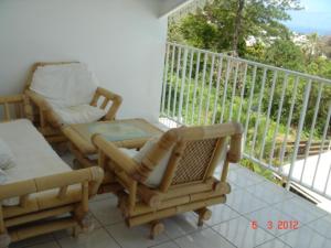 a balcony with a couch and chairs on a balcony at Appartement spacieux à Bois des Nèfles, 70 m², piscine partagée in Le Bois de Nèfles