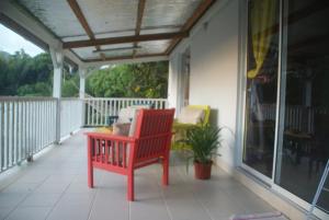 a red rocking chair sitting on a porch at Studio avec vue sur la mer à Fort-de-France 50 m² exceptionnel ! in Fort-de-France
