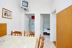 a dining room with a table and a tv on a wall at Charming apartment in Kampor with private garden - 28 m² in Kampor
