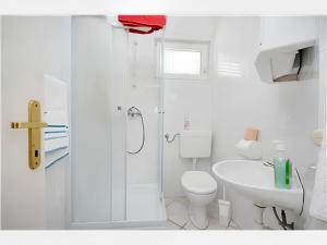 a white bathroom with a toilet and a sink at Charming apartment in Kampor with private garden - 28 m² in Kampor +4 photos
