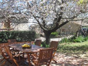 a wooden table and chairs under a tree with flowers at Quaint house in Murlo with shared pool in Murlo