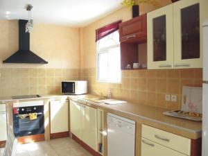 a kitchen with a stove and a microwave at Spacieuse villa à Deshaies avec piscine privée in Deshaies