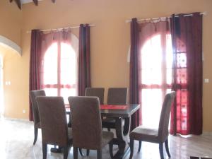 a dining room with a table and chairs and two windows at Spacieuse villa à Deshaies avec piscine privée in Deshaies +39 photos