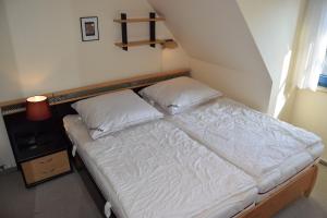 a bed with white sheets and pillows in a room at Waack, Brigitte App Nr 7 in Schönberger Strand