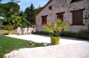 a patio with chairs and a building with flowers at Maison charmante à Saint-Cirq avec piscine privée in Saint-Cirq