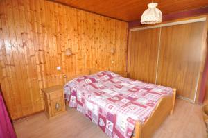 a bedroom with a bed and a wooden wall at Appartement confortable à La Chapelle-d'Abondance 75 m² avec jardin in La Chapelle-dʼAbondance