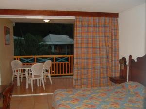a bedroom with a bed and a balcony with a table and chairs at Studio charmant à Sainte-Anne de 25 m² avec terrasse et jardin. in Sainte-Anne
