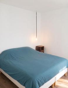 a bed in a bedroom with a blue comforter at Appartement charmant à Algajola avec terrasse in Algajola