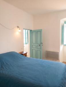 a bedroom with a blue bed and a door at Appartement charmant à Algajola avec terrasse in Algajola