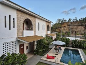 a couple sitting under an umbrella next to a house at Snuggy Hostel Kuta in Kuta Lombok