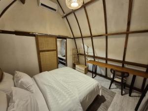 a bedroom with a bed and a desk in a room at Snuggy Hostel Kuta in Kuta Lombok