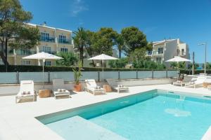 a swimming pool with chairs and umbrellas next to a building at Bauló Mar Apartments in Can Picafort