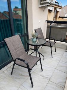 two chairs and a table on a balcony at Alta Vista Apollonia Sunset in Sozopol