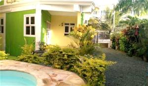 a green house with a swimming pool in front of it at Charming Apartment in Pereybere with Shared Pool, 75 m² in Pereybere