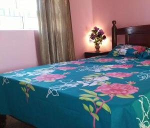 a bed with a blue blanket with flowers on it at Charming Apartment in Pereybere with Shared Pool, 75 m² in Pereybere