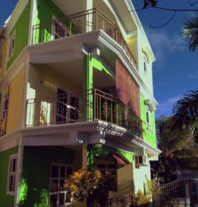 a green and white building with balconies and palm trees at Charming Apartment in Pereybere with Shared Pool, 75 m² in Pereybere