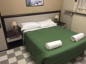 een slaapkamer met een groen bed en handdoeken bij Hotel Eva in Milaan