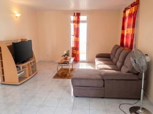 a living room with a couch and a tv at Appartement spacieux au Vauclin de 150 m² avec vue montagne in Le Vauclin