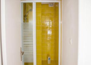 a bathroom with a shower with yellow tile on the wall at Maison charmante avec vue sur lac à Thil-sur-Arroux in Thil-sur-Arroux