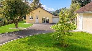 a house with a driveway and a tree at Maison charmante avec vue sur lac à Thil-sur-Arroux in Thil-sur-Arroux