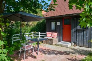 a table and chair with an umbrella in front of a house at Tiny House Gerswalde in Gerswalde
