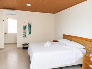 a bedroom with a white bed with a wooden ceiling at Lighthouse Pipa in Tibau do Sul +26 photos