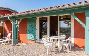 a patio with white chairs and a table in front of a building at Maison cosy avec piscine privée à Estibeaux 38 m² in Estibeaux