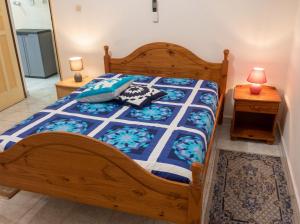 a bedroom with a wooden bed with a blue and white comforter at Appartement spacieux à Petit Canal - 65 m² - Vue sur jardin in Petit-Canal