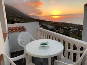 a white table and chairs on a balcony with a sunset at Cozy apartment with sea view in Frontera in Frontera