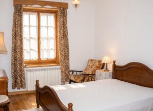 a bedroom with a bed and a chair and a window at Charming villa with mountain view in Pedraça, pool in Pedraça