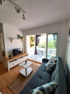 a living room with a blue couch and a television at Charming apartment with mountain view in Francàs - 45m² in Comarruga