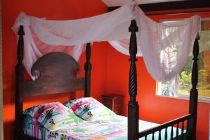 a bedroom with a bed with a canopy and a window at Bungalow charmant avec vue sur la mer à Sainte Rose in Sainte-Rose