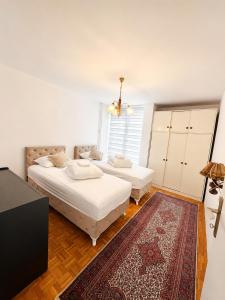 a bedroom with two beds and a rug at Riverside Apartment, 10min Airport in Sarajevo