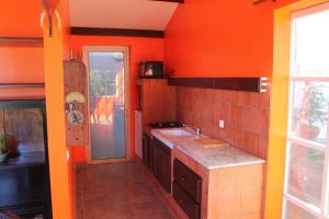 a kitchen with orange walls and a sink at Bungalow charmant avec vue sur la mer à Sainte Rose in Sainte-Rose