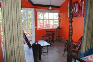 a room with orange walls and a table and chairs at Bungalow charmant avec vue sur la mer à Sainte Rose in Sainte-Rose +6 photos