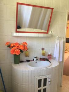 a bathroom sink with a mirror and a vase of flowers at Spacious Apartment Sintra 120 m² + Pool in Sintra