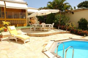 a patio with a table and chairs next to a pool at Villa élégante à Sainte-Anne avec piscine privée ouverte toute l'année in Sainte-Anne +40 photos