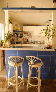 a kitchen with two stools in front of a counter at Villa élégante à Sainte-Anne avec piscine privée ouverte toute l'année in Sainte-Anne